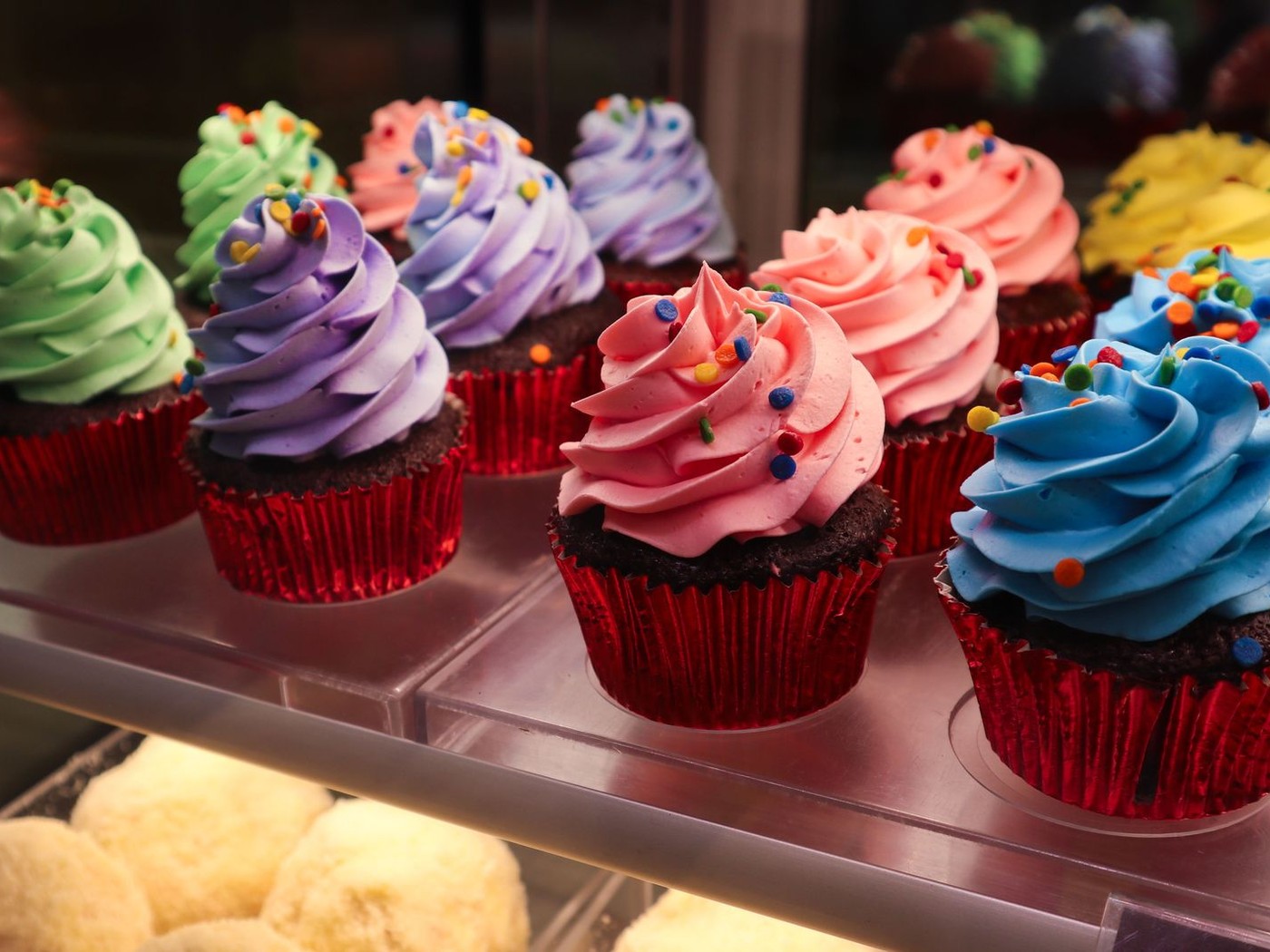 Freshly frosted cupcakes lined up in a bakery display case